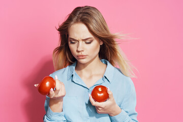 woman in blue shirt holding tomatoes fun food pink background