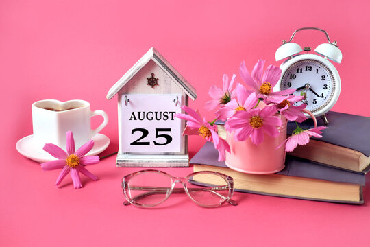 Calendar for August 25 : the name of the month of August in English, the number 25, a cup of tea, books, a bouquet of pink flowers, glasses for vision, an alarm clock on a pink background