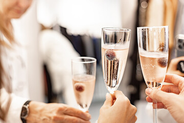 Beautiful female hands are holding glasses of champagne or rose wine. Close-up. Women clink glasses. New Years celebration, event or party. Soft focus. Human hands.