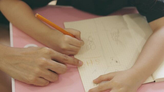 Close up 4K of asian mom is teaching her adorable child daughter focusing on hands writing for homework and homeschool education shows concept of parental love and togetherness who alway support. 