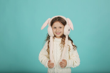 a beautiful happy brown-haired girl with curly hair in a white sweater with pink bunny ears on a blue background
