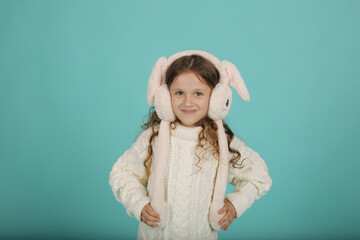 a beautiful happy brown-haired girl with curly hair in a white sweater with pink bunny ears on a blue background