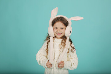 a beautiful happy brown-haired girl with curly hair in a white sweater with pink bunny ears on a blue background