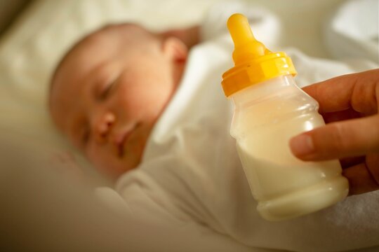 A Mother Holding A Bottle Of Milk To Feed Her Baby. Formula And Breast Pumping.