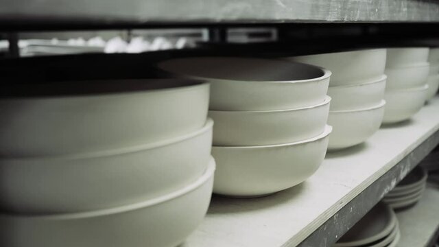 Molds for ceramic dishes are on the shelves of production and ceramics harden in them. The camera moves along the rack with molds for ceramic dishes. High quality 4k footage