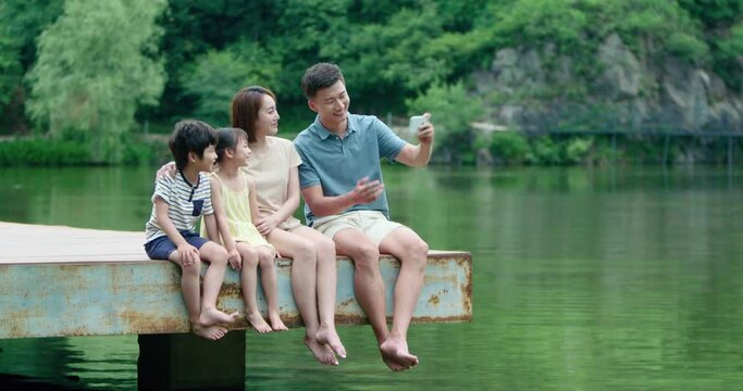 Happy young Chinese family taking selfie with smartphone outdoors,4K