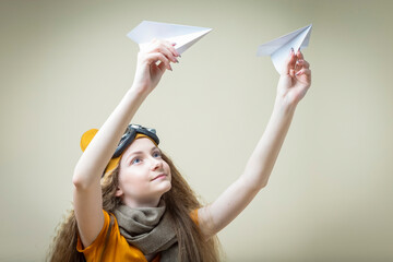 Positive Caucasian Teenage Girl in Flying Glasses Launching Pair of Origami Paper Planes Over Beige Background.