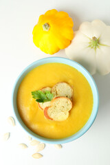 Pot with pumpkin soup and ingredients on white background