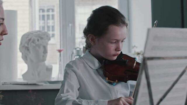 A girl playing violin by the notes