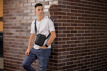 Man holding his new messenger bag leaning at wall