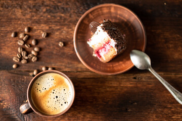 Cup of coffee and a piece of cake on a dark wooden background.