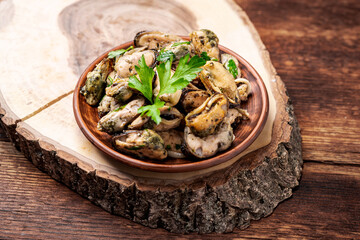 Peeled mussels in sauce on a dark wooden background.