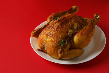 Plate with roast turkey on red background