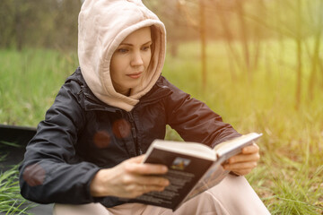 The woman is holding a book in her hands. Reading in the park, in the forest. Rest, training, relaxation concept.