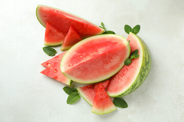 Watermelon slices and mint leaves on white textured table