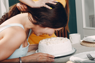 Young woman dips face in white cake with cream. Happy birthday concept