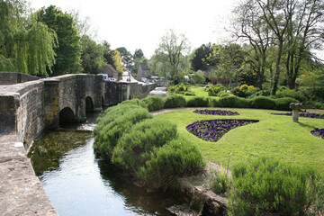 Fototapeta na wymiar The Gardens of the Swan Hotel and the River Coln in Bibury, Gloucestershire in the UK