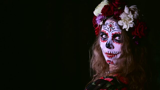 Woman in santa muerte makeup on a black background. Girl wearing traditional mexican holy death costume for halloween.