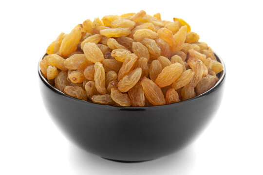 Close-up of organic golden long size raisins (dry grapes )in a black ceramic bowl over white background.