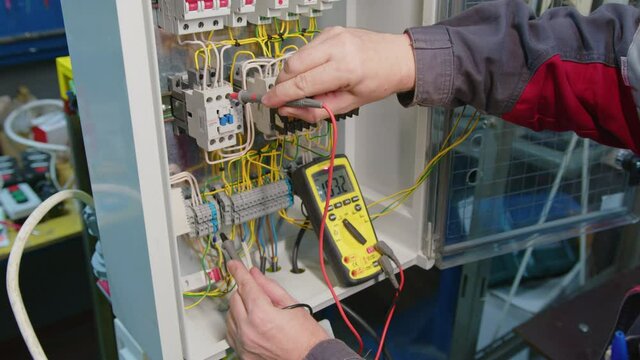 Electricians hands testing current electric in control panel. Electrician engineer work tester measuring voltage and current of power electric line in electical cabinet control.