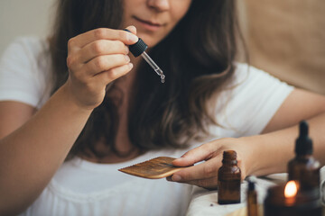 Young woman applying natural organic essential oil on hair and skin. Home spa and beauty rituals.