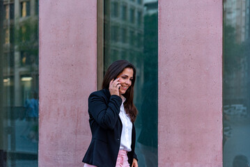 Fototapeta premium Caucasian businesswoman talking by mobile phone in the city