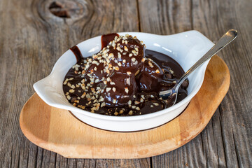 profiteroles dessert on a wooden background. Profiterole dessert filled with chocolate and hazelnut kernels