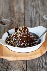 profiteroles dessert on a wooden background. Profiterole dessert filled with chocolate and hazelnut kernels