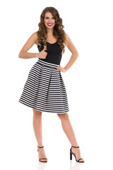 Confident Young Woman In Striped Mini Skirt And High Heels Is Showing Thumb Up
