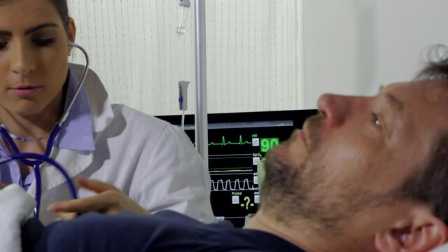 Female doctor cheking heart of ill man in hospital