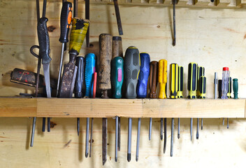 Phillips and flat screwdrivers hanging on wooden wall