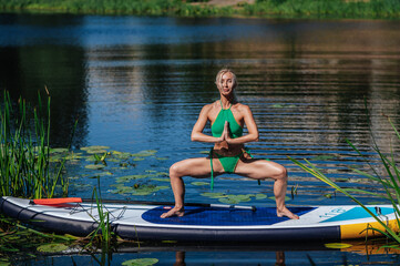 Girl in green on a sup board doing yoga