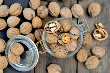 top view  on shelled walnuts in a glass jar among others on wooden table