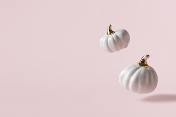 Two levitating white decorative pumpkins on light pink background with copy space. - 451375857