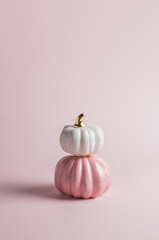 Two decorative glossy pumpkins standing vertically on top of each other on pink background. - 451375879