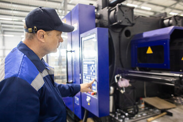 A worker presses a button and starts an automatic manufacturing process in a factory