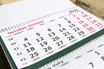 Planning a business calendar for October 2021 paper wall business concept with English and Russian...