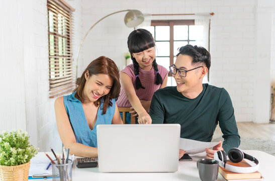 Happy Asian family using computer laptop together on desktop at home office..