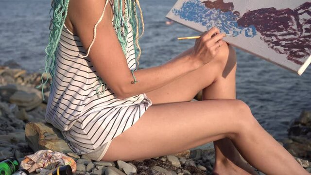 Woman artist paints the sea on canvas. Painting, contemporary artist paints a picture in nature