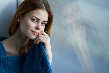 pretty woman sitting near the window with a blue plaid smile at home