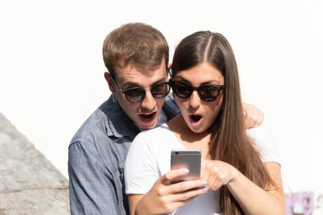 Young surprised couple looking to a smartphone. Social media content reaction