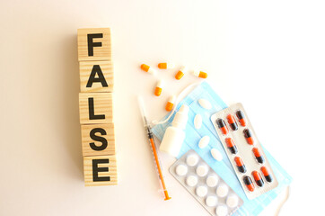 The word FALSE is made of wooden cubes on a white background. Medical concept.