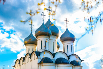 Domes with Eastern Orthodox crosses on a white church against a blue sky with clouds Orthodox Faith. Symbol of Christianity, prayer, repentance for sins. 