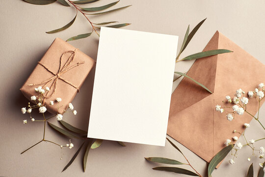 Greeting Card Mockup With Gift Box, Envelope And Eucalyptus And Gypsophila Twigs On Beige Background.