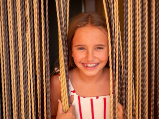 Portrait of a young caucasian girl with braces smiling through the curtains