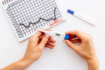 Basal temperature calendar with hands holding ovulation home test