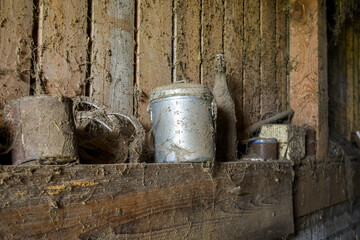 vintage metal milk jug with spider webs and dust around, stored in an old barn with bottles and farm items 