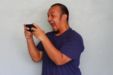 Asian young man angry expression while playing mobile games