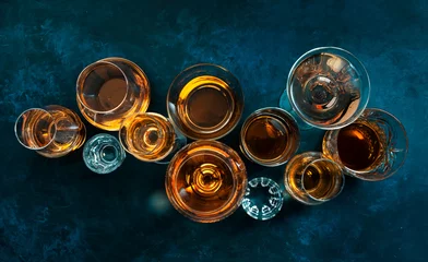 Poster Strong alcohol drinks, hard liquors, spirits and distillates iset in glasses: cognac, scotch, whiskey and other. Blue background, top view © 5ph