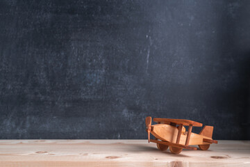 A wooden toy airplane stands on the background of a chalk board. Copy space
